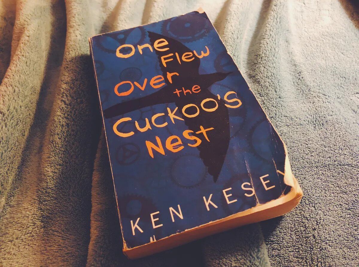 Cover novel One Flew Over The Cuckoo’s Nest dengan latar biru tua dan gambar burung berwarna hitam